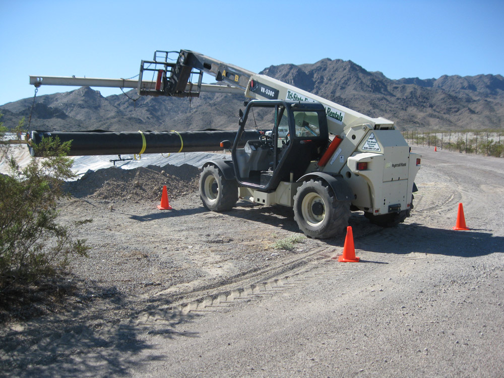 A white and black forklift transporting heavy pipes
